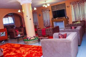 ein Wohnzimmer mit Sofas und Stühlen sowie einem TV in der Unterkunft C & G house in Nairobi