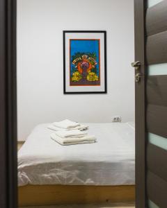 a bed with white sheets and a picture on the wall at Ultra Central Minimal and Cozy Apartment in Bacău +26 photos