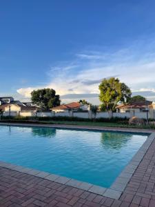 una piscina de agua azul frente a las casas en 2-BR Apt, Pool access & Balcony, Paulshof, en Sandton