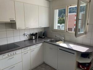 a kitchen with white cabinets and a sink and a window at Superspot Ferienwohnung mit Super Aussicht in Churwalden +7 photos