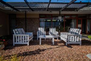 four white chairs and a table on a patio at Mopama Manor in Swellendam