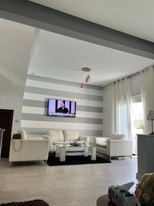Una sala de estar con muebles blancos y un televisor de pantalla plana. en villa azur, en Dar Bouazza
