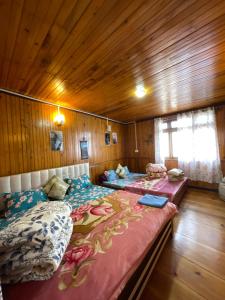 two beds in a room with wooden walls at Radhakunj Homestay in Darjeeling