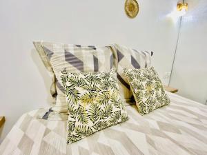 a bed with two pillows on top of it at Sun7 appart T2, avec piscine partagée, logement moderne et cosy in Petit-Bourg +46 photos