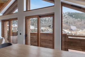 a dining room with a table and large windows at Chalet Grand Lac in Chandon