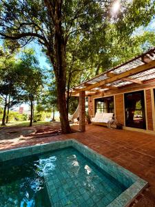 a swimming pool in front of a house with a tree at Casa Bambú - Brisas del Lago in Puerto Bossetti