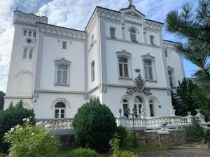 um grande edifício branco com uma cerca em frente em Chateau Franz em Osek