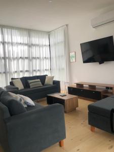 a living room with two couches and a flat screen tv at Casa en Barrio Costa Esmeralda Pinamar in Costa Esmeralda