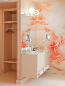 a bathroom with a white sink and a painting at Rose Hôtel Invisible in Quebec City