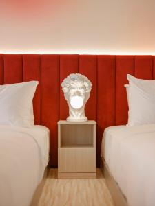 a white vase sitting on a night stand between two beds at Rose Hôtel Invisible in Quebec City