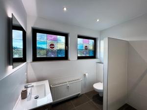 a bathroom with a toilet and three windows at Design-FeWo Sonnendeck in Winterberg +28 photos