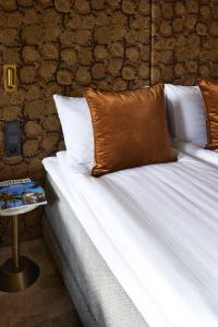 a bed with white sheets and a brown pillow on it at EZE BEACH Residence in Éze