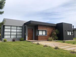 a house with a black and wooden facade at Casa en Barrio Costa Esmeralda Pinamar in Costa Esmeralda