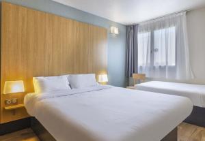een hotelkamer met twee bedden en een raam bij B&B HOTEL PERPIGNAN Nord Aéroport in Perpignan