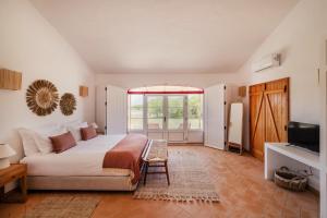 a bedroom with a bed and a large window at Monte da Bemposta in Porto Covo