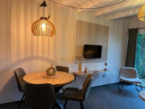 Un comedor con mesa y sillas y un televisor. en Gezellig authentiek 4 persoons huis vlakbij Valkenburg, en Voerendaal