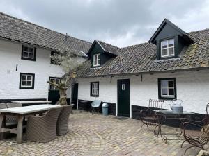 a white house with a patio and a table and chairs at Authentiek 4 persoonshuisje vlakbij Valkenburg in Voerendaal