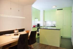 a kitchen with green cabinets and a wooden table with chairs at Apartment right next to ski lift in Parpan