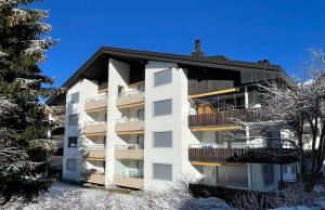 a white apartment building with snow on the ground at Apartment right next to ski lift in Parpan