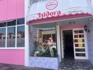 阿里卡Hotel y Restaurant ISIDORA的一栋粉红色的建筑,正面挂着商店招牌。