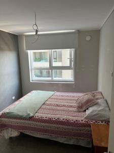 ein Bett in einem Schlafzimmer mit Fenster in der Unterkunft Departamento céntrico temuco in Temuco
