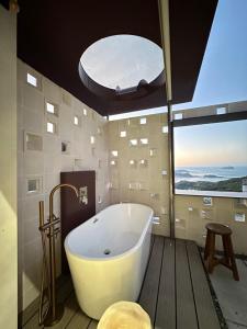 een badkuip in een badkamer met een groot raam bij Jiufen 35 in Jiufen