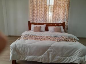 a large bed with white sheets and pink pillows at Goshen Villa Taita in Voi