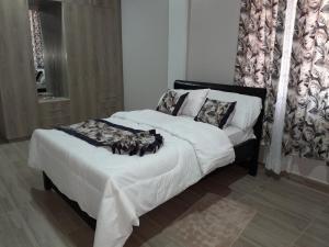 a bedroom with a bed with white sheets and pillows at Goshen Villa Taita in Voi