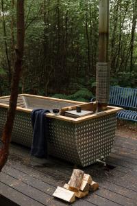 une baignoire assise sur une terrasse en bois avec des bûches dans l'établissement Number 4 Steading Cottage, à Banchory