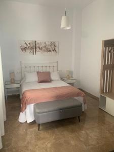 ein Schlafzimmer mit einem großen Bett mit einer grauen Ottomane in der Unterkunft Apartamento Cerezo in Carmona