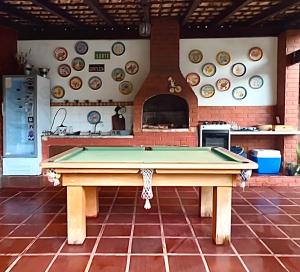 a pool table in a kitchen with plates on the wall at Hostel 040 in Itaipava