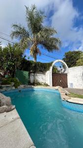 a swimming pool in front of a house with a palm tree at Solar Mediterráneo casaquinta in Santo Tomé