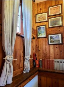 a bedroom with wooden walls and a window with curtains at La Comba - Les Fleurs in Cerise