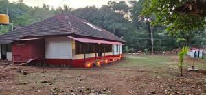 a small red and white building in a field at Taramrata homestay Gokarna in Gokarna