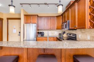 eine Küche mit Holzschränken und einer Granitarbeitsfläche in der Unterkunft Stonegate Resort Unit C105 in Kelowna
