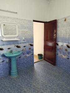 La salle de bains est pourvue d'un lavabo et d'une porte avec des oiseaux sur le mur. dans l'établissement Thavika O Nila Resort & Convention Centre, à Yelagiri