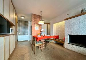 ein Esszimmer mit einem roten Tisch und einem Kamin in der Unterkunft MCX Vacation Rental - Maison Cian, Appartamento con balconi panoramici nel cuore di Breuil Cervinia in Breuil-Cervinia