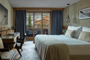 a bedroom with a bed and a desk and a window at Miiro The Mansard in Gstaad