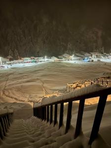 una spiaggia coperta di neve di notte con una recinzione di Ayder Villa de Pelit Hotel ad Ayder Yaylasi