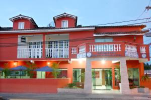 a red building with white balconies on a street at Ancoradouro Hotel - Centro De Porto Seguro in Porto Seguro