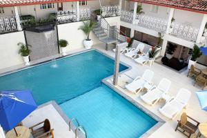 a large swimming pool with chairs and an umbrella at Ancoradouro Hotel - Centro De Porto Seguro in Porto Seguro