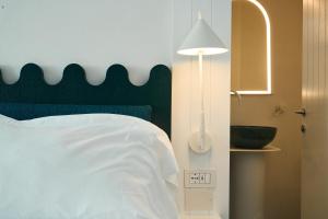 a bedroom with a bed with a green headboard and a lamp at CALEA Boutique Hotel in Bacoli