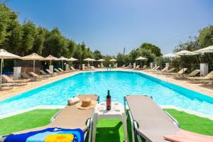 a swimming pool with chairs and a bottle of wine at Nissaki Sea View Hotel in Corfu