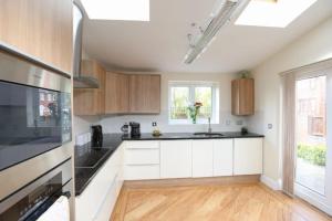 una cucina con armadietti bianchi e ripiani neri di Coundon Fields a Allesley