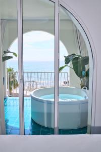 a bath tub in a bathroom with a view of the ocean at CALEA Boutique Hotel in Bacoli