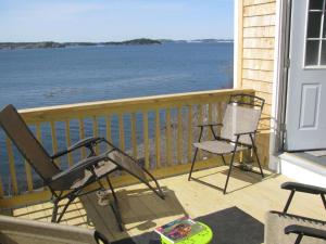 a porch with two chairs and a view of the water at Mudges Bluff Waterfront Retreat in Lubec