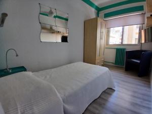 a bedroom with a white bed and a chair at Piso recien reformado in Zaragoza