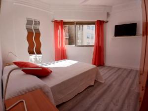a bedroom with a bed with red curtains and a window at Piso recien reformado in Zaragoza