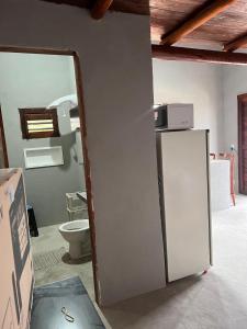 a bathroom with a toilet and a white refrigerator at Pousada Califa Taíba in São Gonçalo do Amarante