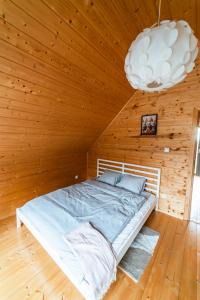 a bed in a wooden room with a chandelier at Nad brzozowym stawem in Kościerzyna